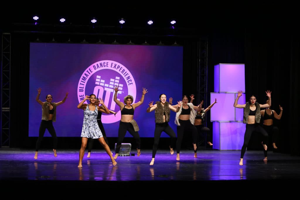 A group of dancers performing a routine on stage at an On The Floor event