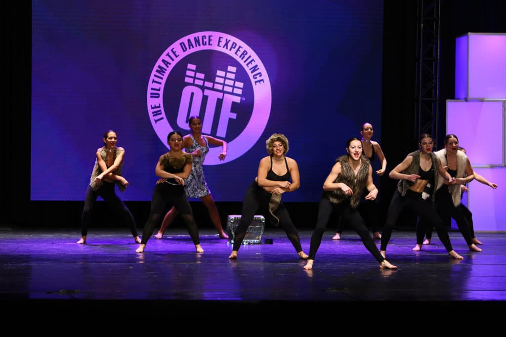 A group of dancers performing a routine on stage at an On The Floor event